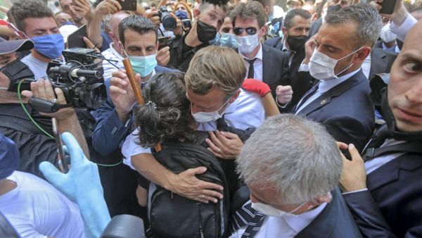 A Lebanese youth hugs French President Emmanuel Macron during a visit to the Gemmayzeh neighbourhood, which has suffered extensive damage due to a massive explosion in the Lebanese capital. AFP