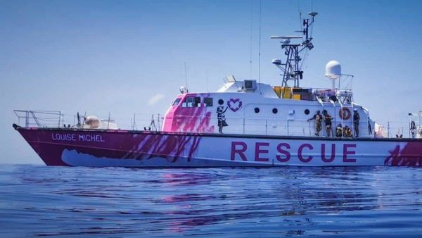 Painted in bright pink and featuring Banksy artwork depicting a girl in a life vest holding a heart-shaped safety buoy, the Louise Michel sails under a German flag. (Twitter Photo)