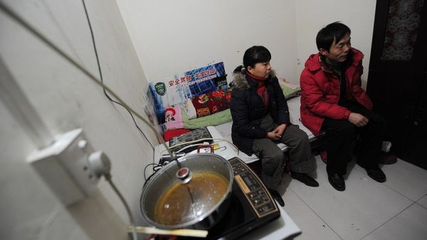 Chinese migrant worker Li Youhong (right) sitting with his wife Qi Shulai in their tiny room, three storeys down in a dimly lit civil defence shelter (AFP)