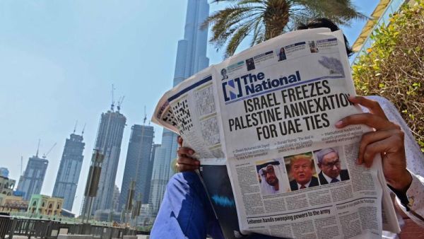 A man reads a copy of UAE-based The National newspaper near the Burj Khalifa, in the gulf emirate of Dubai on August 14. (AFP)
