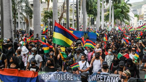 People hold up national flags as they protest against the government's response to the oil spill disaster that happened in early August near the prime minister's office in Port Louis, Mauritius, August 29, 2020. (AFP)