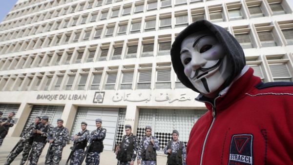 A demonstrator looks on as Lebanese policemen stand guard outside the Central Bank in Beirut last year (AFP)