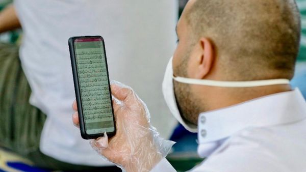Jordanian man wearing gloves uses cell phone to read Koran inside Mohammad al-Tilawy Mosque in capital Amman recently (AFP)