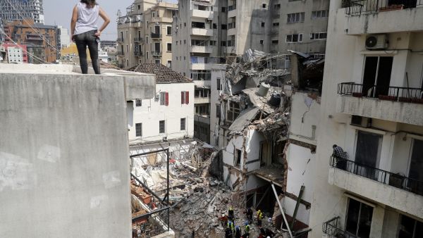 A woman looks on from a rooftop as rescue workers dig through the rubble of a badly damaged building in Lebanon's capital Beirut, in search of possible survivors from a mega-blast at the adjacent port one month ago, after scanners detected a pulse, on September 4, 2020. Lebanese rescuers scoured rubble for a possible survivor in Beirut after the detection of a pulse drew crowds hopeful of a miracle one month on from a devastating explosion. JOSEPH EID / AFP