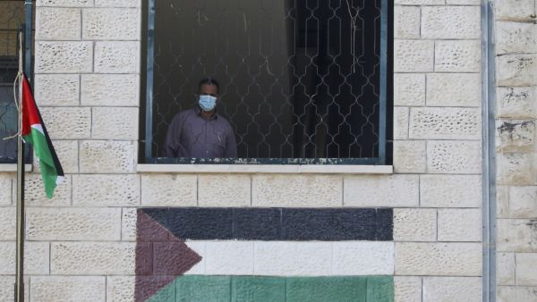 A Palestinian teacher, wearing a protective face mask, looks on from a window on the first day of school in the village of Salem east of Nablus in the occupied West Bank on September 6, 2020, during the coronavirus pandemic. JAAFAR ASHTIYEH / AFP