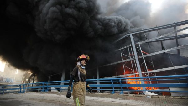 A firewoman walks past smoke billowing from a huge fire that raged in Beirut's port on September 10, 2020, sending a column of black smoke into the sky and sparking alarm among Lebanese still reeling from the devastating dockside blast last month.ANWAR AMRO / AFP