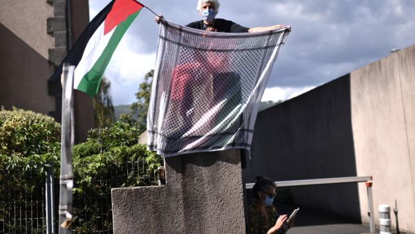 A woman holds a keffiyeh and a Palestinian flag as the pack rides during the 13th stage of the 107th edition of the Tour de France cycling race, 191 km between Chatel-Guyon and Puy Mary, on September 11, 2020. Marco BERTORELLO / AFP