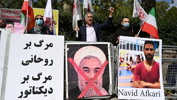 Protesters wave the Lion and Sun flag of the National Council of Resistance of Iran and the white flag of the People's Mujahedin of Iran, two Iranian opposition groups, with a placard depicting the crossed out face of Iran's President Hassan Rouhani as they demonstrate outside the Iranian embassy in London on September 12, 2020 against the execution of Iranian wrestler Navid Afkari in the southern Iranian city of Shiraz and against the Iranian government. Iran said it executed wrestler Navid Afkari, 27, on September 12, 2020 at a prison in the southern city of Shiraz over the murder of a public sector worker during anti-government protests in August 2018. Reports published abroad say Afkari was condemned on the basis of confessions extracted under torture, prompting online campaigns of support for his release.  JUSTIN TALLIS / AFP Protesters wave the Lion and Sun flag of the National Council of Resistance of Iran and the white flag of the People's Mujahedin of Iran, two Iranian opposition groups, with a placard depicting the crossed out face of Iran's President Hassan Rouhani as they demonstrate outside the Iranian embassy in London on September 12, 2020 against the execution of Iranian wrestler Navid Afkari in the southern Iranian city of Shiraz and against the Iranian government. Iran said it executed wrestler Navid Afkari, 27, on