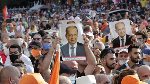 Supporters of Lebanese President Michel Aoun raise portraits of him as they gather near the presidential palace in Baabda, east of the capital Beirut on September 12, 2020, as others protest nearby to denounce a lack of progress in a probe by authorities into a monster blast that ravaged swathes of the capital 40 days ago. ANWAR AMRO / AFP
