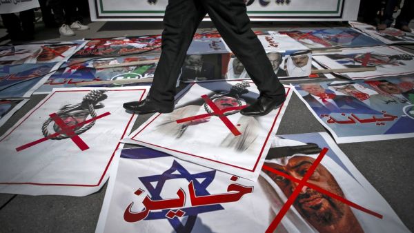 A demonstrator walks on pictures laid out on the ground depicting X-marks over the faces of Bahrain's King Hamad bin Isa al-Khalifa and Abu Dhabi Crown Prince Sheikh Mohammed bin Zayed al-Nahyan (shown before an Israeli flag with the Arabic word "traitor" superimposed), during a protest against the United Arab Emirates' and Bahrain's decisions to normalise relations with Israel, in Gaza City on September 15, 2020. Palestinian leaders had earlier called for demonstrations against the "shameful" deals the Uni