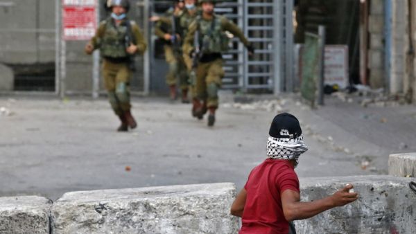 A Palestinian protester hurls stones at Israeli security forces amid clashes in the center of the West Bank city of Hebron, on September 18, 2020. HAZEM BADER / AFP