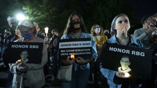 People holds signs and candles as they pay their respects to Ruth Bader Ginsburg near the US Supreme Court in Washington, DC on September 19, 2020. US President Donald Trump vowed to quickly nominate a successor, likely a woman, to replace late Supreme Court Justice Ruth Bader Ginsburg, only a day after the death of the liberal stalwart. Jose Luis Magana / AFP