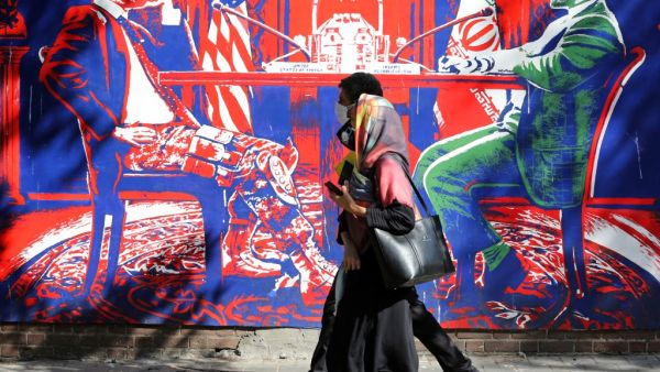 A couple, wearing protective masks amid the COVID-19 pandemic, walks past a mural painted on the outer walls of the former US embassy in the Iranian capital Tehran on September 20, 2020. Iran called on the rest of the world to unite against the United States, after Washington unilaterally declared UN sanctions against the Islamic republic were back in force. Washington has said it will "impose consequences" on any country not complying with the sanctions, although the US is one of the only nations that beli