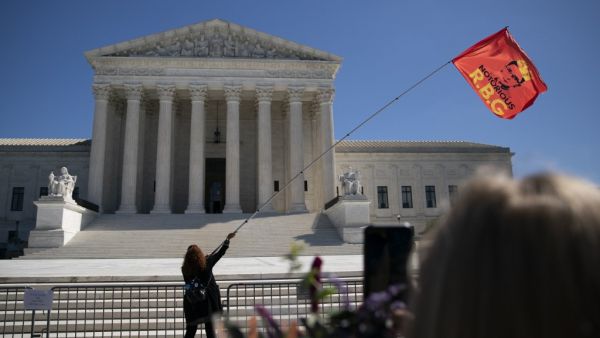 A woman waves an 'RBG' flag outside the US Supreme Court at a makeshift memorial for late US Supreme Court Justice Ruth Bader Ginsburg is seen near the steps of the US Supreme Court on September 21, 2020 in Washington, DC. (AFP)