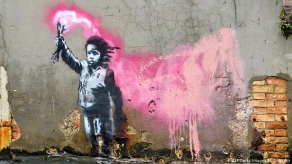 An alleged Banksy work depicts a migrant child wearing a lifejacket holding a pink flare. It is painted on the wall of a house overlooking the Rio de Ca Foscari canal in Venice (AFP/Getty)