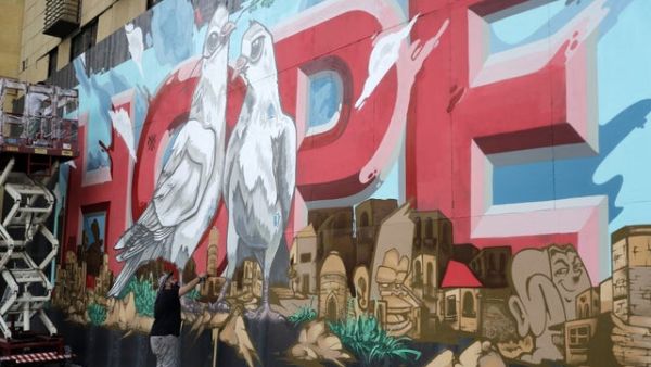 Now the dark surface is decorated by a bright mural centering on the word “hope” in large red letters, with a pair of doves sitting in front. (AFP)