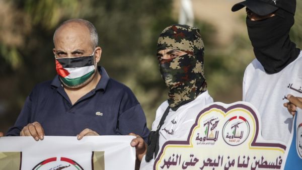 Masked Palestinians of the Popular Resistance Committees hold signs on the 21st anniversary of the group and protesting against the normalisation deal with the UAE and Bahrain, on September 28, 2020 in Rafah in the southern Gaza Strip. SAID KHATIB / AFP