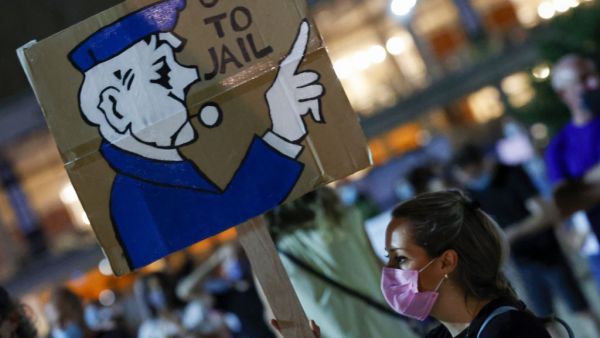 An Israeli anti-government protester carries a placard during a demonstration against Prime Minister Benjamin Netanyahu and against the second nationwide lockdown imposed by the government in a bid to stem the increase of COVID-19 infection cases, in the coastal city of Tel Aviv, on October 3, 2020. JACK GUEZ / AFP