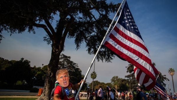 A man wearing a mask of US President Donald Trump holds a US flag during a pro-Trump rally in Beverly Hills, California on October 3, 2020. Apu GOMES / AFP