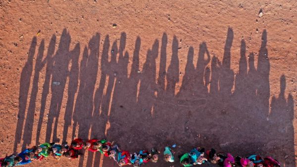 An aerial view taken on October 6, 2020, shows displaced Syrian youths standing in a queue ahead of classes, after tents were transformed to classrooms, at a camp for the internally displaced in the town Maarrat Misrin in Syria’s northwestern Idlib province. Omar HAJ KADOUR / AFP