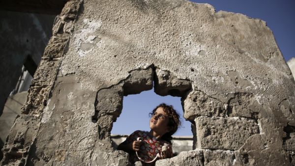 A Palestinian girl is pictured behind a whole at her destroyed family's house in Gaza City, on October 8, 2020. MOHAMMED ABED / AFP