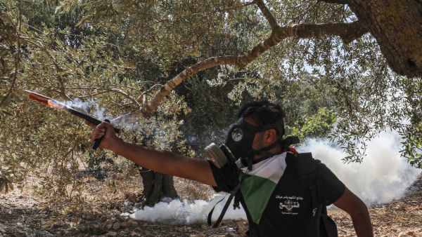 A mask-clad protester wearing a Fatah youth-labelled t-shirt shoots firecrackers during clashes between Palestinian protesters and Israeli forces following a demonstration against Jewish settlements in the town of Asira Shamaliya in the occupied West Bank near Nablus on October 9, 2020. ABBAS MOMANI / AFP