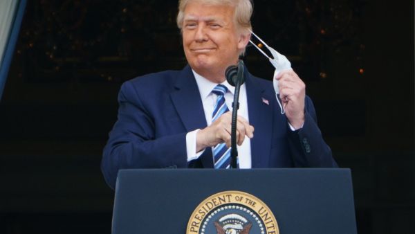 US President Donald Trump takes his mask off before speaking from the South Portico of the White House in Washington, DC during a rally on October 10, 2020. Trump spoke publicly for the first time since testing positive for Covid-19, as he prepares a rapid return to the campaign trail just three weeks before the election. MANDEL NGAN / AFP