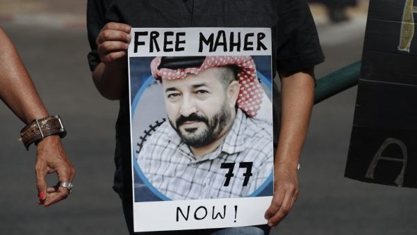 Israeli left-wing activists lift a placard bearing the picture of Palestinian administrative detainee Maher al-Akhras during a demonstration calling for his release after his health has deteriorated while on hunger strike for 77 days, in front of Kaplan medical center where he is in Israeli custody, in the central city of Rehovot, on October 11, 2020. Ahmad GHARABLI / AFP