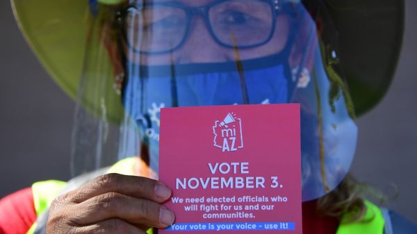A Democratic Party canvasser holds up campaign material while knocking on doors in the suburbs of Phoenix, Arizona, October 15, 2020 to encourage people to vote in the November 3 presidential and congressional elections. The canvassers, many of whom lost their jobs in LA because of the pandemic, earn up to 20 dollars an hour and keep their health insurance. Their main focus has been to zoom in on working-class neighborhoods where voter turnout is usually low, but the Biden activists also venture into more w
