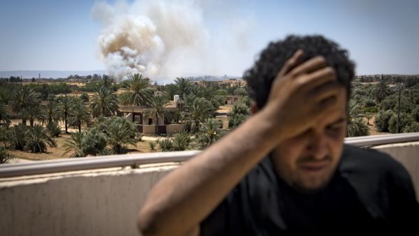 In this file photo taken on April 29, 2019, a fighter loyal to the internationally-recognised Government of National Accord (GNA) stands on a rooftop as smoke rises in the distance during clashes with forces loyal to strongman Khalifa Haftar, in Espiaa. (AFP)