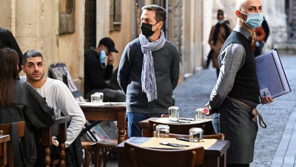 People sit at a restaurant's terrace in downtown Rome as a waiter looks on, on October 25, 2020, as the country faces a second wave of infections to the Covid-19 (the novel coronavirus).  (AFP/File)