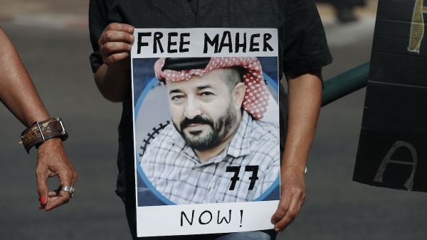 Israeli activists lift a placard bearing the picture of Palestinian administrative detainee Maher Al-Akhras during a demonstration calling for his release on October 11, 2020 [AHMAD GHARABLI/AFP via Getty Images]