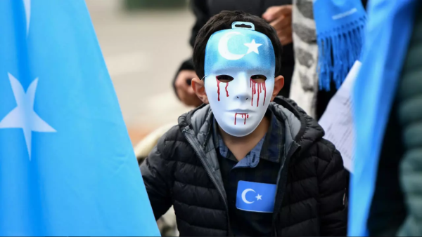 A boy wearing a blue mask with tears of blood takes part in a protest march of ethnic Uighurs, in Brussels on April 27, 2018, asking for the European Union to call upon China to respect human rights. (Emmanuel Dunand, AFP)
