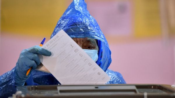 A woman wearing a face mask and gloves casts her ballot at a polling station during Moldova's presidential election in Chisinau on November 1, 2020, amid the ongoing coronavirus disease pandemic. Sergei GAPON / AFP