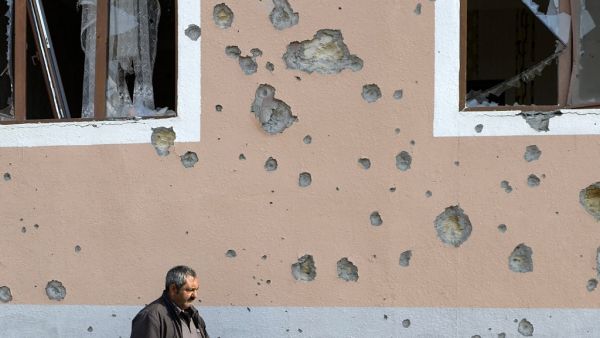 A man walks in front of a residential building damaged in shelling during the ongoing military conflict between Armenia and Azerbaijan over the breakaway region of Nagorno-Karabakh, in the town of Terter on November 1, 2020. TOFIK BABAYEV / AFP