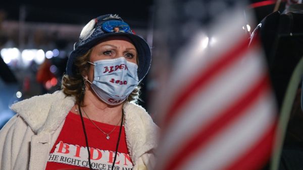 A supporter of Democratic presidential nominee and former Vice President Joe Biden looks at partial election results on a giant screen outside the Chase Center in Wilmington, Delaware on November 3, 2020. ROBERTO SCHMIDT / AFP