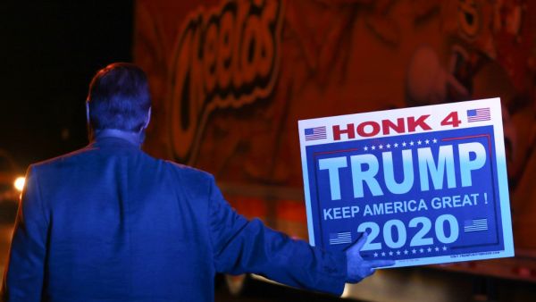 Under the blue light from a police car parked behind him, Andy Danevicius holds a Trump 2020 sign in front of a Cheetos truck as he protest the Nevada vote along with other Trump supporters outside Clark County Election Department on November 5, 2020, in North Las Vegas. Danevicius, who hails from Canada, said that he became a US Citizen last year to be able to vote in this election. Ronda Churchill / AFP