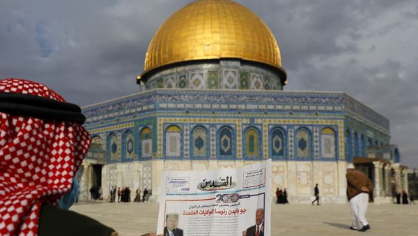 A Palestinian man reads the front page of Al-Quds newspaper, headlined in Arabic "Joe Biden the new US President" in front of the Dome of the Rock in the al-Aqsa mosque compound, Islam's third holiest site, in the old city of Jerusalem on November 8, 2020. AHMAD GHARABLI / AFP