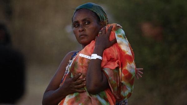 An Ethiopian refugee who fled fighting in Tigray province carries her baby as she walks at the Um Rakuba camp in Sudan's eastern Gedaref province, on November 21, 2020. AFP