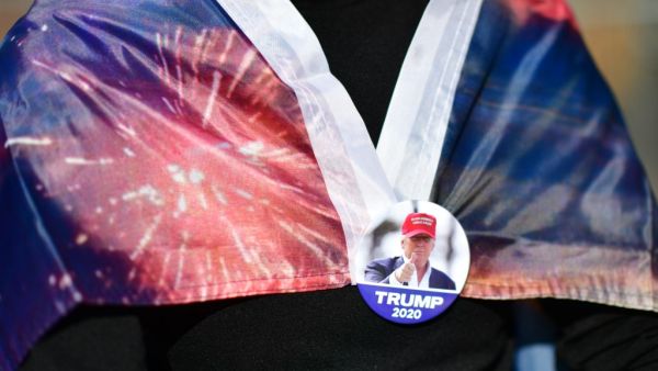 A supporter of President Donald Trump wears a campaign-themed pin to clasp a flag while demonstrating outside of where votes are still being counted, six days after the general election on November 9, 2020 in Philadelphia, Pennsylvania. The state was called for President-elect Joe Biden on Saturday, propelling him past the requisite 270 electoral votes to win the presidency. With 98% of the ballots reported, President-elect Biden leads President Trump by 45,595 votes. Mark Makela/Getty Images/AFP Mark Makel