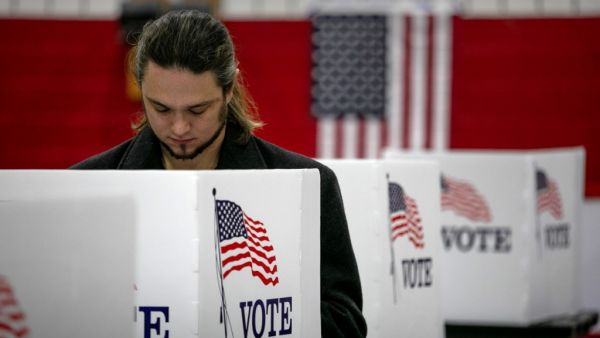 An maskless voter fills in his ballot on November 03, 2020 in Lansing, Michigan. After a record-breaking early voting turnout, Americans went to the polls on the last day to cast their vote for incumbent U.S. President Donald Trump or Democratic nominee Joe Biden in the 2020 presidential election. JOHN MOORE / GETTY IMAGES NORTH AMERICA / Getty Images via AFP