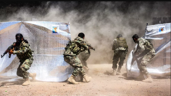 Turkish-backed Syrian fighters perform manoeuvres past tents with posters showing the flags of the Kurdish People's Protection Forces (YPG) during a military exercise on Syria’s northern border with Turkey. (Nazeer al-Khatib, AFP)
