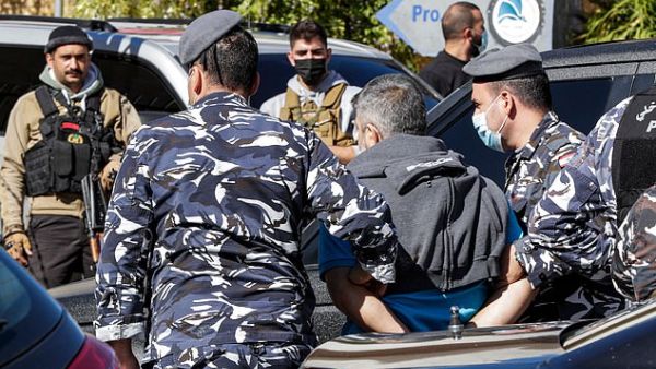 The police in Beirut confirmed 15 inmates has been re-arrested so far and four had handed themselves in. Pictured: Police escort a prisoner who had fled a detention centre. (AFP)