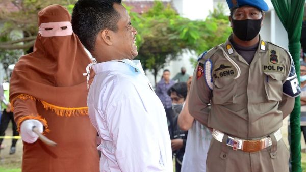 A child rapist cries out and grimaces as he is publicly flogged by a member of the sharia police after he was found guilty of raping and molesting a minor in Indonesia's ultra-conservative Aceh province. AFP