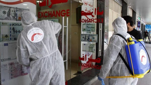 Volunteers with Lebanon's Disaster Management Unit disinfect a currency exchange in the southern city of Saida on March 12, 2020 to prevent the spread of coronavirus. AFP