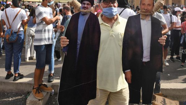 Man holds cut-outs of Hezbollah leader Hassan Nasrallah, left, and former foreign minister Gebran Bassil (AFP) Man holds cut-outs of Hezbollah leader Hassan Nasrallah, left, and former foreign minister Gebran Bassil (AFP)
