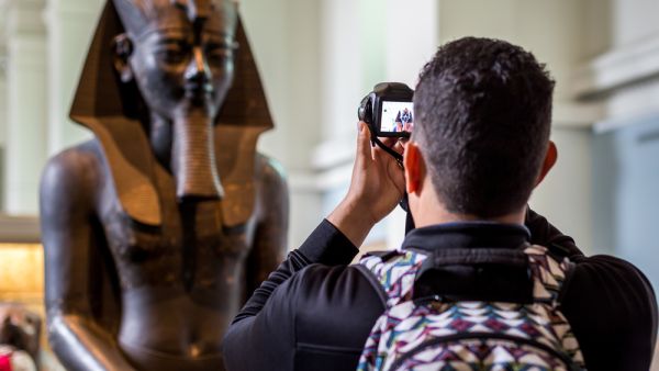 A tourist taking photo of an egyptian status brought from Egypt and kept in British Museum of London. (Shutterstock/ File Photo)