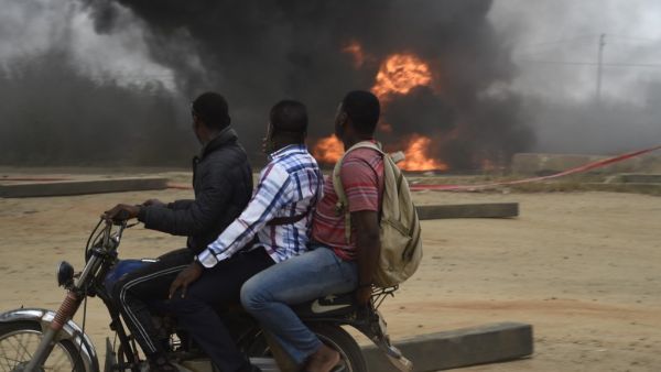 A taxi motorcyclist, popularly called Okada, drives past a tanker laden with petrol that is on fire after it fell over and spilt the contents across the Lagos-Ibadan expressway in Magboro, Ogun State, on December 2, 2020.PIUS UTOMI EKPEI / AFP