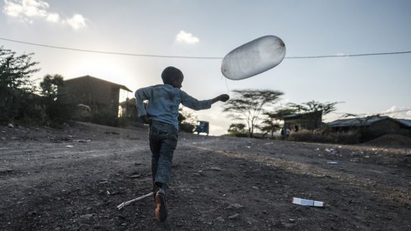 A boy runs with a balloon in the village of Bisober, in Ethiopia's Tigray region on December 9, 2020. The November 14 killings represent just one incident of civilian suffering in Bisober, a farming village home to roughly 2,000 people in southern Tigray.  EDUARDO SOTERAS / AFP