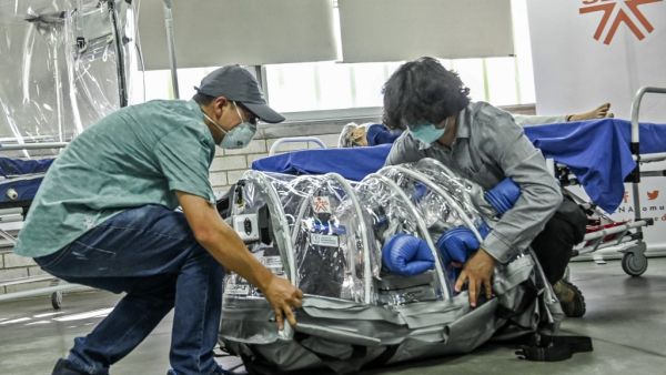 A student and a professor demonstrate how a depressurized cabin designed to transport COVID-19 patients works in Medellin, Colombia, on December 16, 2020. The cabin was designed and developed by an alliance led by the Ministry of Science, the National University and the SENA technical college. JOAQUIN SARMIENTO / AFP